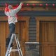 Man putting up Christmas lights outside house